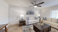 Located at 1000 N Donahue Dr in Auburn, AL, this well-appointed one-bedroom, two-bathroom unit offers a thoughtfully designed single-floor layout. The open-concept living area features wood-look flooring, neutral gray walls, and a ceiling fan, creating a bright and comfortable atmosphere. The living room flows seamlessly into the kitchen, which is a standout feature of the space — showcasing rich dark cabinetry, granite countertops, a tile backsplash, stainless steel appliances including a refrigerator, microwave, range, and dishwasher, and a generous kitchen island with pendant lighting that doubles as a dining area. The spacious primary bedroom accommodates a full suite of furniture comfortably and includes a ceiling fan and direct access to a dedicated closet outfitted with dual wire shelving systems for ample storage. The two bathrooms each offer their own character: one features a dark espresso vanity with granite countertops and wood-look flooring, while the second includes a full tub-shower combo with clean white surround. Consistent wood-look flooring and neutral tones throughout the unit create a cohesive, modern aesthetic well-suited for comfortable everyday living.