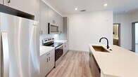 Located at 2311 Odell School Rd in Charlotte, NC, this thoughtfully designed single-story home offers three bedrooms, two bathrooms, a living room, and a well-appointed kitchen — all finished with a clean, modern aesthetic throughout. Light-toned luxury vinyl plank flooring runs seamlessly across every room, complementing the bright white walls and recessed lighting that keep the space feeling open and airy.

The kitchen is a standout feature, showcasing sleek gray cabinetry, white quartz countertops, a subway tile backsplash, and a full suite of stainless steel appliances. A central island with an undermount sink and matte black faucet provides additional prep space and a natural gathering point.

The primary bathroom is well-equipped with a large vanity topped with quartz counters, an illuminated mirror, a wall-mounted medicine cabinet, and a walk-in glass-enclosed shower with white subway tile. The second bathroom features a matching subway tile surround with a soaking tub and matte black fixtures. The bedrooms are bright and well-proportioned, each benefiting from natural light through blinds-fitted windows. A dedicated walk-in closet with built-in shelving adds practical storage. The home's cohesive, contemporary design makes for a polished and functional living environment.