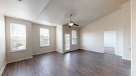 This single-story, two-bedroom, two-bathroom residence offers a thoughtfully designed layout with a blend of practical finishes and comfortable living spaces throughout. The open living area immediately draws attention with its vaulted ceiling, ceiling fan with light fixture, and dark hardwood-style flooring that extends throughout the main areas. Multiple windows fitted with blinds allow generous natural light to fill the space, while a private entry door provides direct outdoor access.

The kitchen is a functional highlight, featuring white raised-panel cabinetry, granite-style countertops, a classic subway tile backsplash, and stainless steel appliances including a range, microwave, and refrigerator. A peninsula with an integrated sink adds additional prep and seating space, while soaring ceilings above lend an airy, open feel to the cooking area.

Both bedrooms are carpeted and equipped with ceiling fans and windows offering outdoor views. The primary bathroom includes a granite-topped vanity, tub-shower combination, and access to a walk-in closet. The second bathroom mirrors similar finishes with a tub-shower combo, wood-style flooring, and a granite vanity, providing consistent quality throughout the home.