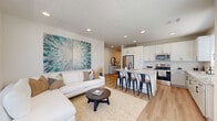 Located at 380 Wire Drive in Lakeland, Florida, this single-story, 3-bedroom, 2-bathroom home offers a clean, modern design with a bright and cohesive aesthetic throughout. A welcoming entryway with wood-look flooring leads into the open-concept living and kitchen area, where natural light pours in through large windows dressed with wood-slatted blinds. The living room offers a comfortable, airy ambiance, complete with recessed lighting and an adjacent balcony view. The kitchen is a standout feature, showcasing white shaker-style cabinetry with matte black hardware, granite countertops, a classic subway tile backsplash, stainless steel appliances, and a central island with bar seating — ideal for casual dining and entertaining. The three bedrooms are carpeted for comfort, each featuring ceiling fans and natural light from dual windows. The primary bedroom includes a spacious walk-in closet with built-in wire shelving. Both bathrooms are finished with granite vanity countertops, undermount sinks, and matte black fixtures, with the full bath featuring a tiled tub-shower combination. A dedicated laundry room with side-by-side full-size washer and dryer rounds out this practical and stylish home.