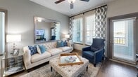 This thoughtfully designed 2-bedroom, 3-bathroom residence in Orlando, Florida offers a comfortable and stylish single-floor layout. The open-concept kitchen is a standout feature, showcasing light wood cabinetry, granite countertops, a mosaic tile backsplash, stainless steel appliances, and a central island with bar seating — all flowing seamlessly into the living and dining areas. The living room is bright and welcoming, with large windows dressed in patterned drapery, hardwood-style flooring, and access to an outdoor balcony. Both bedrooms feature plush carpeting, bold teal accent walls, large windows with outdoor views, and dedicated closet space. The primary bedroom is generously sized and bathed in natural light. The bathrooms are well-finished with tile flooring, granite vanity countertops, light wood cabinetry, large mirrors, and a soaking tub with tile surround. Two walk-in closets provide ample storage throughout. The overall aesthetic is cohesive and modern, combining neutral tones with vibrant accents, creating an inviting and functional living environment suited for Orlando's lifestyle.