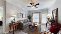 This thoughtfully designed single-floor residence offers two bedrooms and two bathrooms within a comfortable and efficiently laid-out floor plan. The inviting living room features crown molding, hardwood-style flooring, and a ceiling fan with light fixture. Natural light flows in through large windows with white plantation shutters, and a glass-paneled exterior door provides additional brightness and outdoor access. The dining area is a standout architectural feature, boasting a tray ceiling with a chandelier and elegant white decorative columns that frame the space beautifully. The kitchen is well-equipped with stainless steel appliances, including a range, microwave, and dishwasher, complemented by white cabinetry and granite-style countertops over tile flooring. The primary bedroom offers generous space with hardwood-style floors, a walk-in closet with wire shelving, and a ceiling fan. The en-suite bathroom includes granite countertops, a vanity with mirror, and a tub-shower combination with tile surround. The second bedroom similarly features a ceiling fan and convenient closet access. Two dedicated closets throughout the home provide ample storage. The overall ambiance is warm and classic, with consistent finishes that lend cohesion across the entire residence.