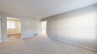 This single-floor residence offers a clean, functional layout designed for comfortable everyday living. The interior is finished with neutral gray and beige tones throughout, creating a cohesive and understated aesthetic. Soft wall-to-wall carpeting covers the living and bedroom areas, while durable wood-look flooring runs through the kitchen and laundry spaces.

The living area is generously proportioned, featuring a textured ceiling, HVAC venting for climate control, and a front entry door accompanied by a window that allows natural light to fill the space. The kitchen is thoughtfully updated with crisp white shaker-style cabinetry, light stone-look countertops, a classic white subway tile backsplash, a built-in dishwasher, and a single-basin sink — offering both style and practicality.

The bedrooms are well-sized with neutral carpeting and natural light from windows fitted with blinds. At least one bedroom includes a full-width reach-in closet with a rod and shelf for organized storage. The bathroom features a full soaking tub and shower combination surrounded by elegant marble-look tile, along with a window for ventilation. A dedicated laundry area accommodates a full-size washer, adding significant in-unit convenience to the overall layout.