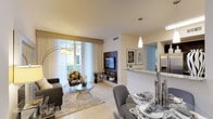 This thoughtfully designed single-floor residence offers a seamless blend of modern style and functional living. The open-concept living and dining area forms the heart of the space, featuring light tile flooring, neutral toned walls, and floor-to-ceiling sliding glass doors dressed with sheer white curtains that invite an abundance of natural light and provide views of lush tropical greenery and a private balcony. A wood-paneled feature wall anchors the living area, adding warmth and visual interest.

The kitchen is efficiently laid out with rich dark cabinetry, granite countertops, stainless steel appliances including a range, built-in microwave, and dishwasher. A breakfast bar connects the kitchen to the dining and living areas, enhancing the open flow.

Two well-proportioned bedrooms offer a calm and restful retreat, each finished with the same light tile flooring, neutral walls, and large windows with tailored drapery panels that provide privacy while allowing natural light.

The bathrooms are finished with large-format marble-style tile in warm beige tones. One bathroom features a soaking tub with shower combination and a dark-cabinetry vanity with a white countertop, while the second bath mirrors the refined tile aesthetic. Throughout the residence, the consistent use of neutral tones and quality finishes creates a cohesive, contemporary ambiance.