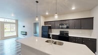 This single-floor unit offers a practical and modern layout across a comfortable footprint, with all living spaces conveniently located on one level. The open-concept kitchen and living area serves as the heart of the home, where a large white quartz island with an undermount stainless steel sink anchors the kitchen. Dark espresso cabinetry pairs with black appliances—including a refrigerator, range, and built-in microwave—while pendant lights with glass fixtures hang above the island, adding a refined touch. The living area features wood-look luxury vinyl plank flooring, recessed lighting, and glass double doors with a transom window that invite natural light and outdoor views.

Both bedrooms are well-sized, each equipped with ceiling fans, windows offering outdoor views, and wood-look flooring. The primary bedroom is notably spacious and includes a large walk-in closet outfitted with multi-tier wire shelving. The two bathrooms each feature dark vanity cabinetry, white countertops, and a full tub-shower combination. Wood-look tile flooring adds a cohesive design element. A dedicated laundry room accommodates a full-size washer and dryer with wire shelving above for additional storage.