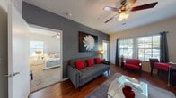 Located at 17203 NW Military Hwy in San Antonio, TX, this single-floor residence offers a thoughtfully designed layout with a cohesive modern aesthetic. The living area serves as the heart of the home, featuring rich hardwood-style flooring, a bold charcoal accent wall adorned with large-scale artwork, and an abundance of natural light streaming through multiple windows dressed with blinds and curtains. Ceiling fans throughout the space enhance both comfort and airflow.

The kitchen is well-equipped with dark wood cabinetry, granite-style countertops, a mosaic tile backsplash, and black appliances, including a full-size refrigerator and dishwasher. A breakfast bar provides additional seating and connects the kitchen to the main living area.

The bedroom is generously sized with plush carpeting, dual windows that bring in natural light, and direct access to a walk-in closet. The room also features a ceiling fan and provides a calm, restful atmosphere.

The bathroom is finished with dark wood vanity cabinetry, a wide mirror, light countertops, hardwood-style flooring, and a full shower-tub combination. Overall, the residence presents a clean, modern design with a cohesive color palette and functional layout suited for comfortable everyday living.