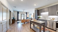 Located on N Oklahoma Ave in Oklahoma City, this 2-bedroom, 2-bathroom residence offers a thoughtfully designed single-level floor plan that balances style and functionality. The open-concept layout seamlessly connects the kitchen and living area, creating an inviting, cohesive space filled with natural light. Hardwood-style flooring runs throughout, lending a warm, contemporary feel to every room.

The kitchen is a standout feature, showcasing sleek gray cabinetry with under-cabinet lighting, a white tile backsplash, granite countertops, and a full suite of stainless steel appliances including a refrigerator, range, microwave, and dishwasher. A central island provides additional prep and storage space.

The living room is bright and airy, with large windows and glass doors that open to a private balcony, offering outdoor views of the surrounding area. The primary bedroom is a comfortable retreat, while the second bedroom features a window with natural light and ample space.

The two bathrooms are clean and modern — one featuring a glass-enclosed walk-in shower with tile surround, and the other offering a full soaking tub with coordinating tile work and wood-look flooring. Together, the rooms form a cohesive, move-in-ready residence with a polished, contemporary aesthetic.