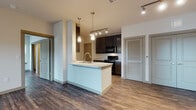 Located at 3701 N Jackson Rd in McAllen, Texas, Unit 311 is a thoughtfully designed single-floor residence that blends modern finishes with functional living spaces. Rich, dark wood-style vinyl flooring extends throughout the unit, creating a warm and cohesive aesthetic from room to room.

The open-concept kitchen serves as the heart of the home, featuring dark espresso cabinetry with brushed nickel hardware, light stone countertops, black appliances, and a central island with a built-in sink and pendant lighting overhead. Track lighting illuminates the kitchen and adjoining living area, while a dedicated space houses a full-size washer and dryer, offering in-unit laundry convenience.

The living area is generously proportioned with neutral walls, a ceiling fan, and natural light streaming through blinded windows. The bedrooms continue the same warm flooring and feature ceiling fans, ample wall space, and access to well-organized closets. The bathroom is fitted with dark cabinetry, stone-topped vanity, wood-style flooring, and a full tub-shower combination with tiled surround. Louvered and paneled interior doors add a refined touch throughout. The overall ambiance is clean, contemporary, and move-in ready.