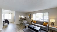 Located at 4300 Echo in La Mesa, this single-floor residence offers a well-designed layout that maximizes both comfort and functionality. The open-concept living area serves as the heart of the home, featuring durable hardwood-style flooring that extends throughout the space, providing a clean and cohesive aesthetic. A large picture window floods the living room with natural light, creating a bright and welcoming atmosphere with views of the surrounding greenery. The living area is thoughtfully connected to the kitchen, which is visible through an open pass-through bar counter complete with bar stool seating — an ideal setup for casual dining or entertaining. The kitchen features white cabinetry and ample counter space, offering a practical and efficient workspace. A textured ceiling adds a classic touch to the interior. Neutral wall tones throughout the space create a versatile backdrop that complements a range of décor styles. The overall ambiance is warm, open, and inviting, making this single-level residence a comfortable and functional home in the La Mesa community.