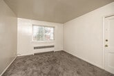 Located at 4925 Franklin Ave in Des Moines, Iowa, this 2-bedroom, 1-bathroom unit offers a compact and efficient single-floor layout. The space features neutral-toned walls and plush carpeting throughout the bedrooms, creating a warm and approachable atmosphere. Both bedrooms are naturally lit by windows with blinds and are equipped with baseboard radiator heating units. The primary bedroom is a well-proportioned space featuring a ceiling fan with light fixture, while the secondary bedroom includes a closet and its own window. The kitchen is a galley-style space with white cabinetry, laminate countertops, a double-basin stainless steel sink, a gas range, and tile flooring. A window above the counter brings in natural light and views of the surroundings. The bathroom retains a classic retro character with pink tile walls accented by black tile trim, a tub-shower combination, a pedestal-style vanity with mirror, and mosaic tile flooring. A connecting hallway links the rooms into a cohesive, navigable layout. Baseboard radiators are present throughout, ensuring consistent heating across the unit. This straightforward, functional space is well-suited for those seeking an accessible and manageable home in a residential Des Moines neighborhood.