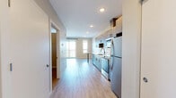 This well-designed one-bedroom, one-bathroom unit at 1001 Belknap St in Superior, Wisconsin offers a thoughtfully laid-out single-floor plan. The open-concept kitchen and living area is a standout feature, with light wood-tone luxury vinyl plank flooring flowing throughout the space. The kitchen is outfitted with modern two-tone cabinetry — warm wood uppers paired with cool gray lowers — complemented by white quartz countertops, a stainless steel refrigerator, electric range, built-in microwave, and dishwasher. A peninsula provides added counter space and casual dining options. The living area is bathed in natural light and opens directly onto a private balcony through sliding glass doors, offering pleasant outdoor views. The bedroom is a comfortable, neutral-toned room with a ceiling fan and its own access to two closets, one of which features wire shelving for organized storage. In-unit laundry adds everyday convenience. The bathroom includes a full tub-shower combo with a curved curtain rod, a vanity with wood cabinetry, and a safety grab bar. Throughout the unit, recessed lighting, clean white trim, and a neutral color palette create a bright, modern ambiance.