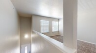 This single-floor residence offers a practical and well-organized layout encompassing two bedrooms, one bathroom, a kitchen, hallway, and staircase. The entry staircase leads to the main living level, where neutral-toned walls, textured ceilings, and wall-to-wall carpeting create a consistent and understated aesthetic throughout the living and sleeping areas.

The galley-style kitchen is efficiently designed with white upper cabinetry, gray lower cabinets, white subway tile backsplash, light-tiled flooring, and white countertops. Black appliances, including a refrigerator, electric range, microwave, and dishwasher, provide a functional contrast to the bright cabinetry.

Both bedrooms feature soft carpeting and white horizontal blinds that allow natural light to filter in. The primary bedroom includes a ceiling fan with integrated lighting, while the secondary bedroom offers a similarly bright, carpeted space. The hallway area contains an electrical panel accessible from the carpeted corridor.

The bathroom is finished with large-format tile flooring, a full tub-shower combination, a gray vanity with white countertop, overhead cabinetry, and a lighted mirror, providing a clean and practical design.