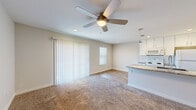 This thoughtfully laid-out 2-bedroom, 1-bathroom unit offers a comfortable and efficient single-floor living experience. The open-concept kitchen and living area serves as the heart of the home, where warm-toned carpet in the living space transitions to wood-look flooring in the kitchen. The kitchen is well-appointed with crisp white cabinetry, granite countertops, a peninsula with a stainless steel sink, pendant lighting, white appliances, and a subway tile backsplash. Natural light flows in through multiple windows and a large sliding glass door fitted with vertical blinds, while ceiling fans throughout ensure year-round comfort. The primary bedroom is generously proportioned, featuring soft carpet, a ceiling fan, a window for natural light, and convenient access to the shared bathroom. The second bedroom is equally inviting, highlighted by a charming white barn door on a black sliding track, adding a touch of farmhouse character. The full bathroom offers a tiled tub-shower combo with classic subway tile surround and wood-look flooring. Clean neutral tones and recessed lighting throughout create a bright, cohesive ambiance that is both modern and welcoming.