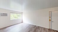 Located at 3583 Alaska Ave in Cincinnati, Ohio, this single-floor unit offers a clean, functional layout across several well-defined spaces. Throughout the unit, wood-look laminate flooring provides a cohesive and easy-to-maintain surface, complemented by crisp white walls that create a bright, neutral backdrop.

The living area is generously proportioned, featuring large windows that frame lush greenery outside, filling the room with abundant natural light. A wall-mounted air conditioning unit and baseboard heating ensure year-round climate control. The open feel of the space is enhanced by the smooth white ceilings and unobstructed sightlines.

The kitchen is a functional and visually distinct space, showcasing bold blue cabinetry across both upper and lower sections, paired with light-toned countertops. Black appliances — including a refrigerator and electric range — and a stainless steel sink complete the setup, offering practical amenities in a compact layout.

The unit includes multiple bedrooms, each with their own window allowing in natural light, neutral walls, and baseboard heating. The bathroom features a full tub and shower combination with white square tile surround and chrome fixtures, delivering a clean and classic finish.

Overall, this unit presents a well-maintained, move-in-ready space with a straightforward layout suited for comfortable everyday living.