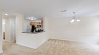 Located at 9125 Thamesmeade Rd in Laurel, Maryland, this single-floor residence offers a well-organized layout designed for comfortable everyday living. The open-concept living and dining area is anchored by soft, neutral-toned carpeting and a chandelier overhead that adds a polished touch to the dining space. A tile-surround fireplace serves as a focal point in the living area, which also benefits from natural light through a window near the entry and access to an outdoor deck via a sliding glass door.

The kitchen is positioned adjacent to the living space and features a peninsula with a dark countertop that provides both prep space and a casual bar-style seating option. Warm-toned wood cabinetry, stainless steel appliances—including a refrigerator, electric range, and built-in microwave—and tile flooring complete the functional kitchen. A chandelier visible from the kitchen reinforces the connection to the dining area.

The bedrooms are carpeted and receive natural light through windows with outdoor views of surrounding greenery. The bathrooms are finished with tile flooring, wood vanities with white countertops, and a full tub-shower combination in one bath, offering practical and clean design throughout.