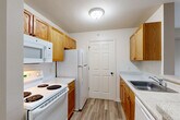 Located at 21901 Stratford Place Boulevard in Brownstown, Michigan, this single-floor, 2-bedroom, 2-bathroom residence offers a functional and comfortable layout across a well-utilized footprint. The open-concept common area connects two living spaces, a dining room, and a kitchen, creating a seamless flow throughout. Light wood-look hard flooring runs through the entry and kitchen areas, while plush carpet covers the living and bedroom spaces, adding warmth underfoot.

The galley-style kitchen is equipped with warm oak cabinetry, a full suite of white appliances including a range, refrigerator, and built-in microwave, along with a stainless steel sink and light stone-patterned countertops. A peninsula counter connects the kitchen to the adjacent dining and living areas. A ceiling fan with light fixture anchors the primary living space.

Both bedrooms feature neutral-toned walls and carpet flooring. The primary bedroom is generously sized and includes closet access, while the second bedroom benefits from a large window that invites natural light. Four closets throughout the unit provide ample storage. Each full bathroom includes a wood-toned vanity with solid countertop, a tiled tub-shower combination, and stone-look tile flooring. A dedicated laundry area with stacked washer and dryer hookups and built-in shelving adds everyday convenience.