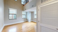 Located at 1001 E Main St in Richmond, VA, this two-story residence offers 2 bedrooms, 2 bathrooms, and a loft spread across two well-proportioned floors. The main level is anchored by a dramatic living area featuring soaring double-height ceilings with an overhead loft-level balcony railing, multiple windows that flood the space with natural light, and warm hardwood flooring that continues throughout the home. The kitchen is well-appointed with granite countertops, white cabinetry, stainless steel appliances including a refrigerator, range, and microwave, and a double-basin sink with views to the outside. Both bedrooms are bright and comfortable, finished with hardwood floors and neutral gray walls; the primary bedroom includes an en-suite bathroom, while the second bedroom features a double-door closet and a window with natural light. The two bathrooms are outfitted with granite vanity countertops, white cabinetry, mirrored medicine cabinets, and tub-shower combinations. Upstairs, the loft level offers flexible open space with hardwood floors and iron-railed stair access. Clean, neutral finishes and consistent hardwood flooring throughout create a cohesive and modern ambiance across the entire home.