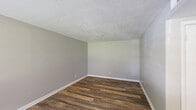 Located at 1800 Augusta Ct in Lexington, Kentucky, this single-floor, one-bedroom, one-bathroom home offers a practical and comfortable layout across a compact yet efficiently designed footprint. Rich, dark hardwood-style flooring runs consistently throughout the main living areas, lending warmth and visual continuity to the space.

The living room greets you at the entry, featuring a front-facing window with blinds that allows natural light to fill the room, along with a ceiling fan for added comfort. Neutral gray walls and a textured ceiling complement the flooring throughout. The space flows openly toward the rest of the home, with clear sightlines down the hallway.

The kitchen is equipped with a refrigerator and an electric range, set against white cabinetry and light-colored walls. Adjacent to it is a utility room that provides additional functional space. 

The bedroom is a well-sized, quiet retreat featuring a large sliding double-door closet, a window overlooking the outdoors, and the same consistent hardwood-style flooring. The full bathroom includes a tub/shower combo with a white surround and built-in shelving niches, paired with a toilet and clean, simple finishes.

Overall, this home presents a clean, move-in ready aesthetic with consistent finishes and a straightforward, easy-to-navigate layout.