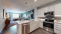 This thoughtfully designed single-floor residence offers a cohesive blend of modern functionality and contemporary style. The open-concept kitchen and living area serves as the heart of the home, where a sleek kitchen features flat-front white cabinetry, stainless steel appliances including a range, microwave, dishwasher, and refrigerator, paired with clean white countertops and a tile backsplash. Pendant lighting accents the kitchen island, which flows seamlessly into the living room, highlighted by a bold teal accent wall and access to an outdoor balcony.

The primary bedroom offers a comfortable retreat with a ceiling fan, a deep green accent wall, balcony access, and a dedicated walk-in closet with built-in shelving and hanging rods. Two full bathrooms are finished with wood-look flooring, clean white fixtures, and tub-shower combinations.

A versatile office features its own teal accent wall, a ceiling fan, and a large window with outdoor views, providing a bright and functional workspace. Wood-look flooring runs throughout the unit, tying each room together with a warm, consistent aesthetic. The overall layout is efficient and well-organized, with a hallway connecting the private spaces to the shared living areas.