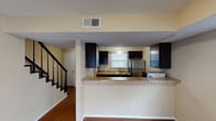 This two-story home is thoughtfully laid out across two levels, offering a functional and comfortable living environment. The main floor centers around an open-concept living and kitchen area, where rich hardwood flooring flows throughout. The kitchen is well-appointed with dark espresso cabinetry, granite countertops, a double stainless steel sink, and stainless steel appliances including a refrigerator and electric range. A peninsula counter separates the kitchen from the living area, creating an ideal space for casual dining or entertaining. The living room is bathed in natural light from multiple windows and a sliding glass door that opens to the outdoors, enhancing the sense of openness. A staircase with a classic black railing connects the main floor to the upper level. Upstairs, the bedrooms feature plush carpeting, ceiling fans, and natural light from well-placed windows. A full bathroom on the upper level includes a tub-shower combination with brushed nickel fixtures. The home's warm, neutral color palette and consistent finishes throughout create a cohesive and welcoming atmosphere across both floors.