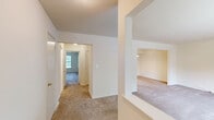 Located at 1100 Village Dr in Somerset, NJ, this one-bedroom, one-bathroom residence offers a comfortable and functional single-floor layout. The living area is finished with neutral wall-to-wall carpeting and crisp white walls, creating a bright, clean atmosphere. A pass-through opening connects the living space to the kitchen, enhancing the sense of openness between rooms. The kitchen is well-appointed with warm wood cabinetry, generous counter space, tile flooring, and white appliances including a gas range and full-size refrigerator. A single window allows natural light to brighten the workspace. The spacious bedroom features plush carpeting, a large sliding closet for ample storage, and a sizable window overlooking lush greenery, bringing the outdoors in. The full bathroom includes a soaking tub and shower combo framed by classic beige tile surround with chrome fixtures, offering a clean and timeless finish. A hallway connects the rooms, providing a logical and efficient flow throughout the residence. Neutral tones and practical finishes throughout make this a move-in ready space suited for comfortable everyday living.