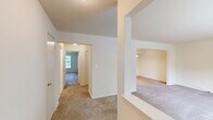 Located at 1100 Village Dr in Somerset, NJ, this one-bedroom, one-bathroom residence offers a comfortable and functional single-floor layout. The living area is finished with neutral wall-to-wall carpeting and crisp white walls, creating a bright, clean atmosphere. A pass-through opening connects the living space to the kitchen, enhancing the sense of openness between rooms. The kitchen is well-appointed with warm wood cabinetry, generous counter space, tile flooring, and white appliances including a gas range and full-size refrigerator. A single window allows natural light to brighten the workspace. The spacious bedroom features plush carpeting, a large sliding closet for ample storage, and a sizable window overlooking lush greenery, bringing the outdoors in. The full bathroom includes a soaking tub and shower combo framed by classic beige tile surround with chrome fixtures, offering a clean and timeless finish. A hallway connects the rooms, providing a logical and efficient flow throughout the residence. Neutral tones and practical finishes throughout make this a move-in ready space suited for comfortable everyday living.