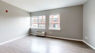Located at 4328 Ridge Ave in Philadelphia's East Falls neighborhood, this modern single-floor unit offers a thoughtfully designed open-concept layout that maximizes its compact footprint. The living area is bright and airy, featuring light wood-style flooring and two large windows that invite natural light and views of the surrounding neighborhood.

The kitchen is a standout feature, showcasing dark walnut-toned cabinetry paired with crisp white upper cabinets and white quartz countertops. A central island provides additional prep space and casual seating, while a light blue tile backsplash adds a subtle pop of color. Stainless steel appliances — including a refrigerator, range, built-in microwave, and dishwasher — complete this well-appointed culinary space. A pendant light fixture overhead adds a contemporary finishing touch.

The bathroom continues the modern aesthetic with large-format linear tile flooring, warm wood-toned wall tile surrounding the soaking tub and shower, and a sleek dark vanity with a white countertop and undermount sink. Brushed nickel fixtures and grab bars add both style and practicality throughout.

Neutral gray walls and consistent light wood flooring unify the space, creating a clean, cohesive atmosphere suited for modern urban living.