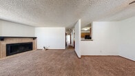 Located at 9211 E Harry St in Wichita, Kansas, this single-floor, 2-bedroom, 3-bathroom home offers a practical and comfortable layout. The open living area is a standout feature, anchored by a corner fireplace with a tile surround and a dark mantel, complemented by a large window that brings in natural light. Plush carpeting runs throughout the living spaces and bedrooms, adding warmth underfoot, while textured ceilings are consistent throughout the home.

The kitchen is efficiently laid out, featuring warm oak cabinetry, a double-basin sink, a breakfast bar pass-through to the living area, and black appliances including a refrigerator and dishwasher. Wood-look flooring in the kitchen provides a practical contrast to the carpeted areas.

The primary bedroom is a generously sized retreat equipped with a ceiling fan and its own dedicated closet space. The second bedroom also features a ceiling fan and a window with natural light. Two walk-in closets provide ample storage throughout the home. The bathrooms feature warm-toned tile flooring, oak vanities with integrated sinks, and tub-shower combinations. A ceiling fan in the main living area adds to the home's practical amenities.