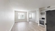 Located at 8737 Baymeadows Rd in Jacksonville, FL, this single-floor unit offers a thoughtfully designed layout with 1 bedroom and 2 bathrooms. The open living area features light-toned luxury vinyl plank flooring, neutral gray walls, and a textured ceiling, creating a clean and modern aesthetic. Natural light filters in through window blinds, enhancing the bright, airy feel of the space. The kitchen is well-equipped with gray shaker-style cabinetry, granite countertops, white subway tile backsplash, and a full suite of stainless steel appliances including a range, dishwasher, and refrigerator. The bedroom is a comfortable size, finished with plush carpet, a large window for natural light, and direct access to a private en-suite bathroom. The en-suite includes a vanity with granite countertops, gray cabinetry, a tub-shower combination with white tile surround, and wood-look tile flooring. A generous walk-in closet with built-in shelving provides ample storage. The second bathroom mirrors the clean, modern finishes found throughout the unit. Overall, the space presents a cohesive, contemporary design with quality materials and practical amenities.