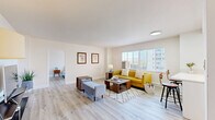 Located on the iconic Wilshire Boulevard in Los Angeles, this 2-bedroom, 1-bathroom residence offers a well-designed, single-level layout with a clean, modern aesthetic throughout. Light wood flooring flows seamlessly across every room, complementing the bright white walls and creating a warm, airy atmosphere.

The spacious living room is bathed in natural light from large windows with slatted blinds, offering views of the surrounding cityscape. The open feel of the room is enhanced by its generous proportions, making it ideal for both relaxing and entertaining.

The kitchen features sleek white cabinetry with high-gloss finishes, white quartz countertops, and a full suite of stainless steel appliances including a gas range, built-in microwave, dishwasher, and refrigerator. A window above the sink brings in additional natural light.

The primary bedroom is a well-proportioned retreat with a large mirrored sliding-door closet and a window overlooking the exterior. The second bedroom is equally bright and comfortable, with ample space and natural light. Four closets in total provide excellent storage throughout the unit.

The bathroom is finished in crisp white tones, featuring a modern vanity with a stone countertop and an enclosed glass shower. Clean lines and polished chrome fixtures complete the refined look of this thoughtfully updated Los Angeles residence.