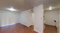 This single-story residence offers two bedrooms and two bathrooms within a practical, well-organized floor plan. The living area features warm wood-style flooring that flows throughout the main spaces, complemented by neutral white walls and a textured ceiling. Vertical blinds cover a sliding glass door or wide window, allowing natural light to brighten the room. A ceiling fan with integrated lighting serves the living area, enhancing comfort and airflow.

The kitchen is positioned adjacent to the living space, separated by a partial wall. It includes white cabinetry offering ample upper and lower storage, white countertops, a stainless steel sink, a dishwasher, and a white range. The wood-style flooring continues into the kitchen, maintaining a cohesive look.

Both bedrooms are carpeted and feature ceiling fans with lighting, windows with blinds for natural light, and closets with built-in shelving and hanging rods for organized storage.

The bathrooms are finished with light tile flooring and include a shower-tub combination, open shelving for linens, a vanity with a sink, and a toilet. The overall design is clean and functional, providing a straightforward, comfortable living environment.