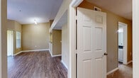 Located at 5009 Park Central Dr in Orlando, FL, this one-bedroom, one-bathroom residence offers a thoughtfully designed layout across a single floor. The open-concept living and kitchen area is anchored by rich wood-style plank flooring that flows throughout the main living spaces, complemented by vaulted ceilings that lend a sense of openness and volume. Large windows and a sliding glass door in the living room invite abundant natural light and provide access to a private balcony with greenery views, creating an airy and inviting atmosphere. A ceiling fan adds both comfort and style to the space. The kitchen is equipped with white cabinetry, dark granite-style countertops, and a stainless steel range with overhead ventilation, offering a clean and functional cooking environment. The bathroom features a wide vanity with white cabinetry, dark countertops, and a well-lit mirror. The bedroom is generously sized, finished with plush carpeting, a ceiling fan with light fixture, and a window that brings in natural light. A dedicated laundry room with a full-size washer and dryer adds everyday convenience. Warm neutral tones carry throughout, creating a cohesive and comfortable living environment.
