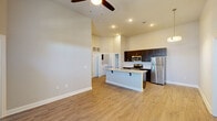 Located at 19216 Dr John Lambert Dr in Hammond, Louisiana, this well-appointed 2-bedroom, 2-bathroom residence offers a thoughtfully designed single-floor layout. The open-concept living and kitchen area immediately impresses with dramatically tall ceilings and a ceiling fan that enhances the sense of spaciousness. Light-toned wood-look flooring flows throughout, complementing the neutral color palette of warm beige and white walls.

The kitchen serves as the heart of the home, anchored by a central island with granite countertops, an undermount sink, and pendant lighting overhead. Dark espresso cabinetry with tile backsplash contrasts beautifully against stainless steel appliances, including a refrigerator, electric range, and microwave. The living area receives natural light through French doors, adding an airy, open feel.

Both bedrooms feature high ceilings, windows with blinds, ceiling fans, and access to closets. The primary bedroom includes a dedicated closet and an en-suite-style layout. The bathrooms are finished with granite-topped dark vanities, wood-look flooring, and a tub-shower combination. A dedicated closet provides additional storage. Throughout the unit, raised panel doors and clean white trim deliver a polished, modern aesthetic.