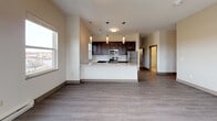 Located on Iron Pier Drive in Syracuse, NY, this single-floor residence offers a thoughtfully designed open-concept layout with modern finishes throughout. The kitchen is a standout feature, equipped with rich dark espresso cabinetry, light granite countertops, a subway tile backsplash, and a full suite of stainless steel appliances including a refrigerator, electric range, and microwave. Stylish pendant lighting hangs above the peninsula, which overlooks the open living area finished with durable wood-style plank flooring. Natural light enters through multiple windows, offering views of the surrounding landscape. The bedrooms are carpeted for comfort, with generous proportions and high ceilings that enhance the sense of space. The primary bedroom suite provides direct access to a full bathroom and a spacious walk-in closet with wire shelving. The bathrooms are finished with light stone-look tile flooring, dark vanity cabinetry, granite countertops, and a tub-shower combination. An additional full bathroom features a tall linen tower cabinet for extra storage. A dedicated laundry area houses a stacked washer and dryer unit for added convenience. The overall aesthetic is clean, contemporary, and move-in ready.