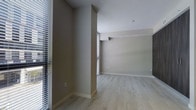 This single-floor space offers a clean, contemporary design characterized by an open and airy layout. The interior is finished with light hardwood-style flooring that runs throughout, complementing the warm neutral taupe tones of the walls to create a cohesive and inviting atmosphere. The open floor plan allows for flexible use of the space, with a naturally flowing layout that connects different areas seamlessly. A structural column adds architectural definition to the interior without compromising the sense of openness. White baseboards provide a crisp contrast against the flooring, adding a polished finish to the overall aesthetic. Horizontal blinds on the windows offer light control while allowing natural light to filter into the space. The ceilings are smooth and bright white, enhancing the sense of height and openness throughout. The minimalist design of the space ensures a versatile canvas, well-suited for a variety of furnishing and décor styles. Overall, the space presents a modern, move-in-ready environment with thoughtful finishes and a functional, well-proportioned layout.