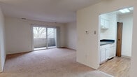 This 2-bedroom, 2-bathroom unit at The Summit in Ann Arbor, Michigan offers a well-organized single-floor layout designed for comfortable everyday living. The open living area is finished with plush wall-to-wall carpeting and connects seamlessly to a private balcony through a full-width sliding glass door, allowing natural light to fill the space and providing pleasant outdoor views of the surrounding neighborhood and trees. A thermostat and light controls are conveniently positioned near the living area.

The galley-style kitchen features white cabinetry, dark countertops, a stainless steel refrigerator, and hardwood-style flooring, offering efficient use of space with ample storage. Both bedrooms are generously sized with soft carpeting, large windows that invite natural light, and closets with built-in hanging rods for organized storage.

Each of the two full bathrooms is clean and functional, featuring white tile tub-surround enclosures with grab bars, dark countertops, white cabinetry, and a full vanity mirror. A dedicated in-unit laundry area houses a full-size washer and dryer alongside a water heater, adding everyday convenience. The overall aesthetic throughout is neutral and bright, creating a practical and inviting living environment.