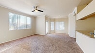 Located at 2155 E Liberty Ln in Phoenix, Arizona, this single-story home offers a comfortable and functional layout throughout. The living area is generously sized, featuring warm neutral carpet, crown molding, and a ceiling fan with light fixture. Multiple vertical-blind windows allow abundant natural light to fill the space, creating a bright and airy atmosphere. An angled corner window bay adds architectural interest to the living area. The bedrooms are carpeted and well-proportioned, each with large windows that bring in natural light. The neutral color palette carried throughout provides a clean and versatile backdrop. The galley-style kitchen is equipped with light wood cabinetry, a full suite of white appliances including a refrigerator, electric range, microwave, and dishwasher, complemented by wood-look vinyl flooring that extends into the bathrooms. The bathroom features a tiled tub-shower combination, wood-look vinyl flooring, and a vanity with countertop storage. A dedicated laundry area houses a full-size side-by-side washer and dryer, adding everyday convenience. Overhead wire shelving in the laundry space provides additional storage. This home presents a practical, move-in-ready layout suited to a variety of lifestyles in the Ahwatukee Foothills area of Phoenix.