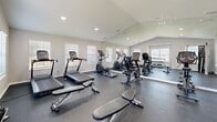 Located at 1421 SW 27th Ave in Ocala, Florida, this fitness center is a purpose-built workout facility spread across a single floor. The space is divided into two connected rooms, each designed to support a comprehensive exercise experience.

The main workout area is the larger of the two rooms, featuring vaulted ceilings that lend an open, airy feel to the space. A full wall of mirrors amplifies the sense of openness and assists with form during workouts. The room is outfitted with a range of cardio equipment, including treadmills and elliptical machines, as well as strength training stations such as a Hoist functional trainer, adjustable benches, and a rack of dumbbells. Recessed lighting and multiple windows fitted with horizontal blinds ensure the space is both well-lit and comfortable throughout the day.

The secondary room provides additional workout space and features track lighting, rubber-textured flooring consistent throughout the facility, and direct exterior access via a windowed door. This area houses additional equipment, including cable machines and free weights, making it well-suited for supplementary or specialized training.

Both rooms are finished with neutral gray walls, clean white trim, and durable speckled rubber flooring ideal for a fitness environment. The overall design is clean, functional, and thoughtfully laid out to maximize usability for a variety of fitness activities.