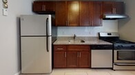 Located at 98 Beech Street in Maywood, NJ, this single-floor unit presents a well-organized layout with a cohesive, neutral color palette throughout. The living and dining areas feature gleaming hardwood floors that reflect natural light streaming in through multiple windows, creating a bright and welcoming atmosphere. Recessed lighting and a radiator heating system are present in the main living space, which connects openly to an adjacent room, enhancing the sense of flow and spaciousness.

The kitchen is thoughtfully appointed with rich, dark wood cabinetry extending to the upper walls for generous storage, granite-style countertops, a subway tile backsplash, and a full suite of stainless steel appliances including a refrigerator, dishwasher, and range. Light tile flooring completes the kitchen's clean, functional aesthetic.

The carpeted bedrooms offer quiet, comfortable retreats, each finished with soft grey walls, white trim, and clean-lined interior doors. The bathroom features a tiled tub-shower combination, a dark wood vanity with a granite-style countertop, wood-look tile flooring, and a window for natural ventilation. Overall, the unit presents a move-in-ready, updated interior with consistent finishes throughout.