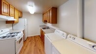 Located at 2093–2095 Durham Rd in Levittown, Pennsylvania, this two-floor residence offers a practical and comfortable layout designed for everyday living. The main living area is generously proportioned, featuring wall-to-wall carpeting and a sliding glass door that invites natural light while providing access to an outdoor space with views of the surrounding greenery. The neutral color palette throughout creates a clean, versatile backdrop. The kitchen is equipped with warm oak cabinetry, ample counter space, and white appliances including a refrigerator and range. A dedicated laundry area houses a full-size washer and dryer alongside additional cabinetry and a utility sink, all set on durable hardwood-style flooring. The bedrooms are carpeted and well-sized, each featuring windows that allow natural light to filter in, creating bright and airy retreats. Two bathrooms are finished with light tile work, vanities with integrated sinks, and grab bar fixtures, with one bathroom featuring a tiled shower and the other offering a tub-shower combination with sliding glass doors. The overall design emphasizes function and comfort, making this a well-rounded residence in a convenient Levittown location.