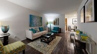 This efficiently designed one-bedroom, one-bathroom residence offers a thoughtful layout that maximizes comfort and functionality throughout its single floor. The combined living and dining area serves as the heart of the home, featuring rich dark hardwood-style flooring, neutral white walls, and ample room for both relaxing and entertaining. A large window allows natural light to fill the living space, creating a bright and welcoming ambiance.

The kitchen is galley-style, outfitted with warm wood cabinetry, light stone-finish countertops, and full-size white appliances including a refrigerator, stove, and dishwasher. Light wood-look flooring ties the space together with a clean, practical aesthetic.

The bedroom is a comfortable retreat finished with plush carpeting, a ceiling fan with overhead lighting, and windows dressed with sheer curtains that invite soft natural light. Two closets provide generous storage throughout the unit.

The bathroom is finished with wood-tone cabinetry, a stone-finish vanity countertop, an overhead storage cabinet, and wood-look flooring, lending a cohesive and tidy feel. A hallway connects the rooms, contributing to the home's logical and easy-to-navigate flow. Overall, the space presents a warm, contemporary character well-suited for comfortable everyday living.