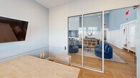 This 270 square foot studio apartment, located at 1050 S Babcock St in Melbourne, FL, showcases a thoughtful design that maximizes its compact footprint. The space is characterized by clean lines, neutral tones, and an abundance of natural light, creating an airy and inviting atmosphere.

The apartment features a versatile open-plan layout, seamlessly integrating the bedroom and living areas. Large windows with horizontal blinds allow ample daylight to flood the space, while offering privacy control. The flooring throughout is a warm, honey-toned hardwood in a herringbone pattern, adding visual interest and a touch of sophistication.

A glass partition wall separates the main living area from what appears to be a small dining or work nook, maintaining an open feel while defining distinct functional zones. The living area is furnished with comfortable blue armchairs and a round coffee table, all resting on a light-colored area rug.

The walls are painted in a crisp white, with a subtle two-tone effect created by a chair rail, adding depth to the room. Carefully chosen artwork adorns the walls, including a large, atmospheric landscape print that contributes to the space's serene ambiance.

Despite its limited square footage, the apartment appears to offer ample storage solutions, though these are not directly visible in the provided images. The overall design ethos focuses on functionality and style, creating a modern and efficient living space ideal for urban dwellers or those seeking a minimalist lifestyle.