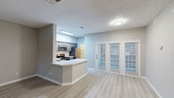 Located at 6000 Ohio Dr in Plano, TX, this two-story, 2-bedroom, 3-bathroom residence offers a thoughtfully designed layout spread across two levels. The main floor features an open-concept kitchen and living area, where light luxury vinyl plank flooring flows throughout. The kitchen is equipped with gray shaker-style cabinetry, white quartz countertops, a subway tile backsplash, stainless steel appliances, and a skylight that fills the space with natural light. A curved peninsula island provides additional prep and seating space. Adjacent to the kitchen, a dedicated pantry offers extra storage convenience. The living room is anchored by a tile-surround fireplace and lined with multiple windows dressed in white blinds, allowing ample natural light. French doors lead to an outdoor area. Upstairs, the two bedrooms feature plush carpeting, ceiling fans, and windows with outdoor views. The primary bedroom includes a walk-in closet with built-in shelving. The three bathrooms are finished with quartz vanity tops, gray cabinetry, framed mirrors, and updated fixtures, with one bathroom featuring a tub-shower combo with tile surround. The overall aesthetic is clean, modern, and move-in ready.