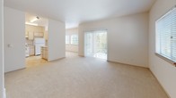 This single-floor unit offers a clean, functional layout designed for comfortable everyday living. The spacious living area is carpeted in neutral tones and bathed in natural light through large windows and a sliding glass door that opens to a balcony, providing pleasant outdoor views. The open connection between the living area and kitchen creates an airy, cohesive feel throughout the main space.

The kitchen is well-appointed with light wood cabinetry offering generous storage, a continuous light-toned countertop, a electric range with overhead ventilation, a full-size refrigerator, and a built-in sink. A peninsula with a passthrough opening connects the kitchen to the adjacent area, adding both prep space and visual openness.

The bedrooms are carpeted and feature neutral walls, creating a calm and versatile environment. Each room benefits from window blinds that allow for natural light while maintaining privacy, and closet access is provided within the rooms.

The bathroom is finished with warm-toned tile flooring and includes a single-sink vanity with light wood cabinetry, a wall-mounted mirror with overhead lighting, a toilet, and a full bathtub with a shower. The overall palette throughout the unit is consistent — warm whites, light woods, and soft neutrals — lending a cohesive and move-in-ready ambiance.
