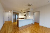 Located in Bellevue, WA, this well-designed 2-bedroom, 2-bathroom residence offers a thoughtfully arranged single-level floor plan with a clean, modern aesthetic throughout. Warm hardwood flooring flows seamlessly across all living areas, complementing the bright, neutral palette and creating a cohesive feel from room to room.

The open-concept kitchen is a standout feature, centered around a generous island with quartz countertops and an undermount sink illuminated by pendant lighting. It is equipped with stainless steel appliances, dark wood cabinetry contrasted by crisp white upper cabinets, and a tile backsplash — all opening directly to the living area, which receives abundant natural light through large floor-to-ceiling windows overlooking the Bellevue cityscape.

Both bedrooms are well-proportioned, with the primary bedroom featuring corner windows that frame urban views on two sides. Each room includes dedicated closet space, with the primary suite offering a spacious walk-in closet with built-in shelving and hanging rods. The bathrooms are finished with subway tile surrounds, wood-toned vanities, and quartz countertops. A dedicated in-unit laundry room with a stacked washer and dryer and built-in wire shelving adds everyday convenience to this polished Bellevue residence.
