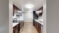 Located at 462 Elkhart St in Aurora, Colorado, this well-appointed 3-bedroom, 2-bathroom single-story home offers a thoughtfully designed layout with modern finishes throughout. The galley-style kitchen is a standout feature, showcasing rich dark espresso cabinetry, stainless steel appliances including a range and refrigerator, white countertops, and a tasteful mosaic tile backsplash — all set over wood-look plank flooring that extends throughout the main living areas. The kitchen opens toward the spacious living room, which is anchored by a marble-surround fireplace, creating a warm and inviting focal point. A sliding glass door provides access to the exterior, allowing natural light to fill the space. The three bedrooms feature plush wall-to-wall carpeting and neutral gray walls, each with windows fitted with blinds for light control and privacy. Multiple closets throughout the home offer ample storage. Both bathrooms are finished with striking marble-style tile surrounds — one featuring a sleek glass-enclosed walk-in shower, the other a full soaking tub — paired with dark wood vanities and wood-look flooring for a cohesive, modern aesthetic. Textured ceilings and clean white trim complete the interior throughout.