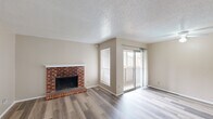 Located in Austin's 78745 zip code, this single-floor, three-bedroom, two-bathroom home offers a practical and comfortable layout throughout. The living room serves as a welcoming centerpiece, featuring wood-look plank flooring, a classic brick fireplace with a white mantel, a textured ceiling, and a sliding glass door that opens to a private balcony, filling the space with natural light. The kitchen runs in a galley-style configuration with ample white cabinetry, granite-look countertops, a double sink, and white appliances, and also connects to the living area via a pass-through breakfast bar with overhead cabinets. Each of the three bedrooms features the same wood-look flooring, neutral toned walls, a textured ceiling, and ceiling fans. The primary bedroom includes access to a closet and is comfortably proportioned. One bedroom offers a sliding glass door leading to an outdoor balcony view. Both bathrooms are finished with granite-look countertops, white cabinetry, and tub-shower combinations. A dedicated closet provides additional storage. Consistent warm neutral tones and low-maintenance flooring create a cohesive feel throughout this efficiently designed Austin home.