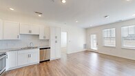 Located at 18183 Wheeler Rd in Westfield, Indiana, this well-designed two-bedroom, two-bathroom single-floor unit offers a clean, contemporary aesthetic throughout. The open-concept kitchen and living area serves as the heart of the home, featuring white shaker-style cabinetry, a subway tile backsplash, granite countertops, and a full suite of stainless steel appliances including a refrigerator, range, microwave, and dishwasher. Light wood-tone luxury vinyl plank flooring runs throughout the main living areas, complementing the bright, white walls and recessed lighting that give the space an airy, modern feel. A door with sidelights allows natural light to flow into the living area. The primary bedroom is a comfortable retreat with plush carpet, a ceiling fan, and a window overlooking the outdoors. It is accompanied by a generously sized walk-in closet outfitted with wire shelving for organized storage. The second bedroom also features soft carpeting, natural light from a large window, and closet access. Both bathrooms are finished with white vanity cabinetry, granite countertops, and wood-tone LVP flooring. One bathroom includes a shower/tub combination, while the second offers a roll-in style shower with a grab bar. The layout is efficient and functional, making excellent use of the available space throughout.