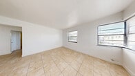 Located at 1930 Marseille Dr in Miami Beach, Florida, this one-bedroom, one-bathroom unit offers a well-organized, single-floor layout designed for efficient and comfortable living. Light-toned ceramic tile flooring runs consistently throughout every room, lending a cohesive and easy-to-maintain aesthetic across the entire space.

The living room is bright and open, featuring multiple windows fitted with horizontal blinds that allow natural light to filter in while maintaining privacy. A wall-mounted air conditioning unit provides climate control, and a main entry door connects the space to the outside. The clean white walls and uncluttered layout give the room a simple, functional character.

The kitchen is equipped with white cabinetry, a stainless steel sink, and striking marble-patterned countertops and backsplash that serve as a standout design element. A window above the sink brings in additional natural light.

The bedroom is a generously sized private retreat featuring two windows with outdoor views of surrounding greenery, a wall-mounted AC unit, and a double-door closet for convenient storage. The room connects smoothly to the hallway, which provides access to additional closet space throughout the unit.

The bathroom includes a full bathtub with shower, a single-sink vanity with white cabinetry, a toilet, and a window for natural ventilation. The tiled flooring continues here, maintaining a consistent look. Three closets distributed across the unit ensure ample storage for residents.