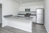 This two-story home in Warren, Michigan offers a well-organized layout across two floors, finished with contemporary materials throughout. The kitchen serves as a functional centerpiece, equipped with stainless steel appliances including a range, over-the-range microwave, and refrigerator. White shaker-style cabinetry pairs with granite countertops, and a peninsula with an integrated sink provides additional workspace and casual seating. Wood-look plank flooring runs throughout the main living areas, contributing to a clean, cohesive aesthetic.

The bathrooms mirror the kitchen's design language, featuring granite-topped vanities with white cabinetry and wood-look flooring. The full bathroom includes a tub-shower combination with a white surround, while the primary bathroom offers a vanity with a large mirror and direct access to a walk-in closet fitted with wire shelving.

The bedrooms are generously proportioned, finished with the same warm wood-look flooring and neutral walls that allow natural light from the windows to brighten each space. Several rooms feature walk-in or pass-through closets, enhancing storage options.

The attached garage provides secure, private vehicle storage with a paneled overhead door and concrete flooring, completing the practical amenities of this well-appointed Warren residence.